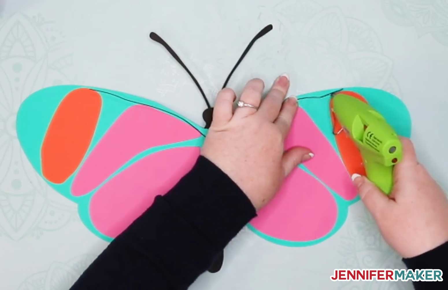 Gluing the wire onto the giant paper butterfly with hot glue