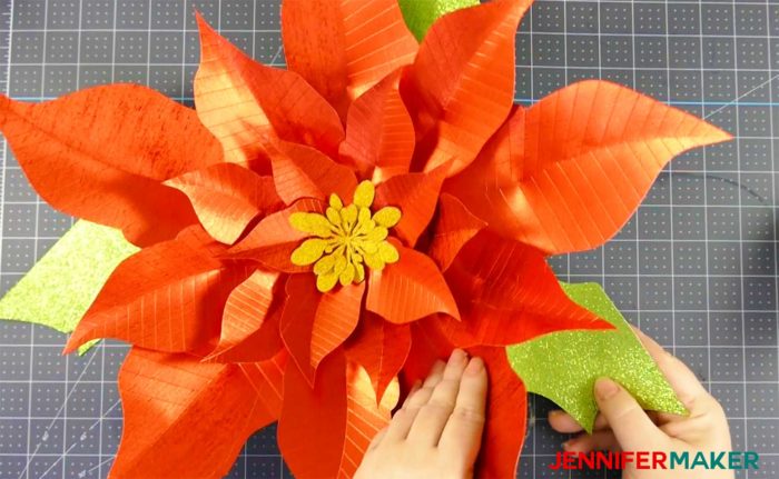 Tucking green paper leaves into the giant red paper poinsettia flower