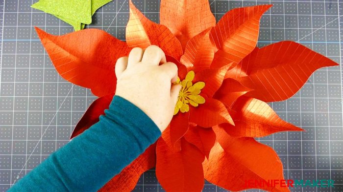 Gluing in a yellow paper poinsettia stamen to make a giant paper poinsettia flower