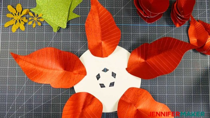 Five paper poinsettia leaves arranged in a star pattern to form a giant paper poinsettia flower