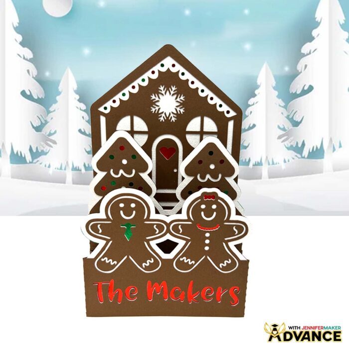 A brown Gingerbread House Pop-Up Card sits on display, with red, green, and white details and little "cookie" people