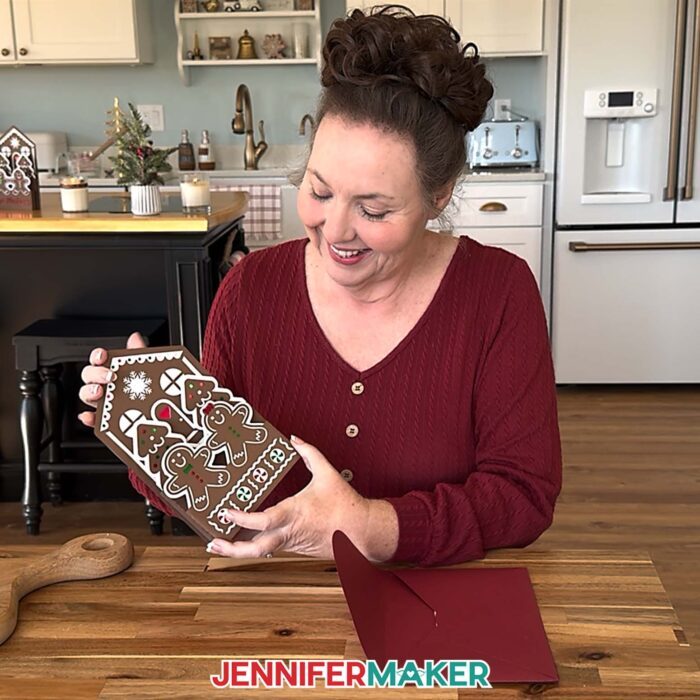 Jennifer Maker sits in her kitchen, showing off the Gingerbread House Pop-Up Card project