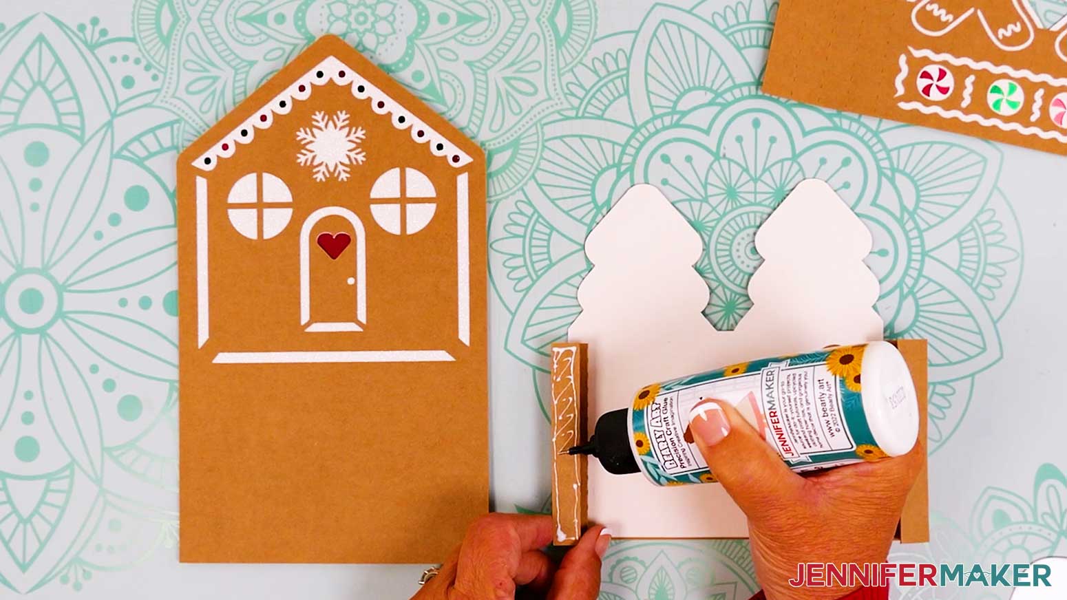 Applying glue to the accordion fold on the left side of the tree tier of the gingerbread house card.