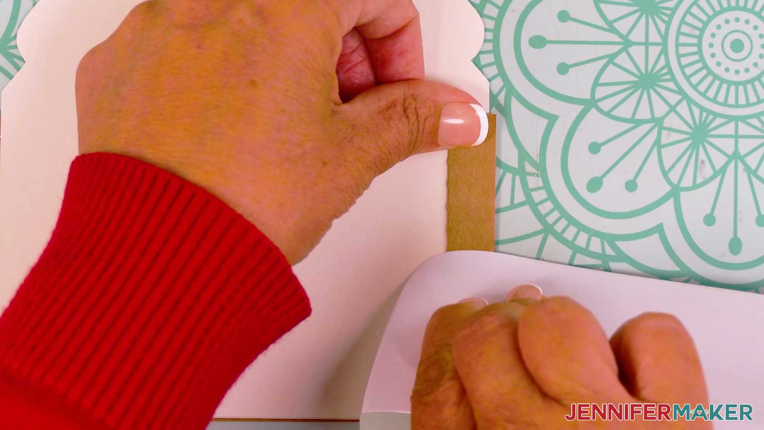 Using a scraper to crease the final fold on the tree tier of the gingerbread house card.
