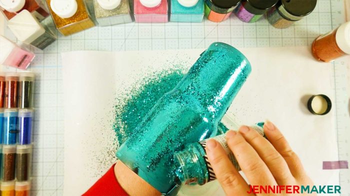 Sprinkling glitter onto a painted tumbler that had Mod Podge on it