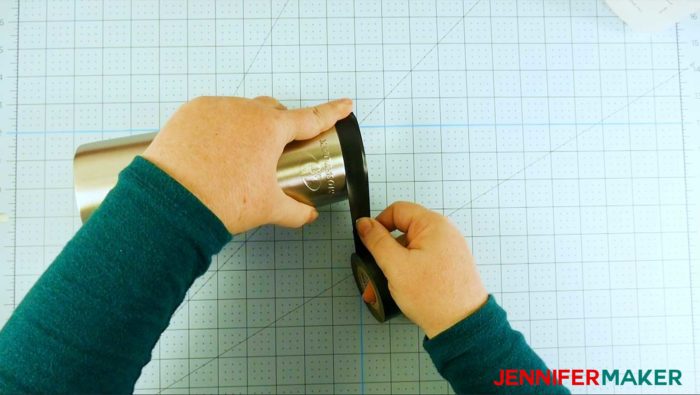 Taping the top of a stainless steel tumbler during step 1 of the glitter tumbler tutorial