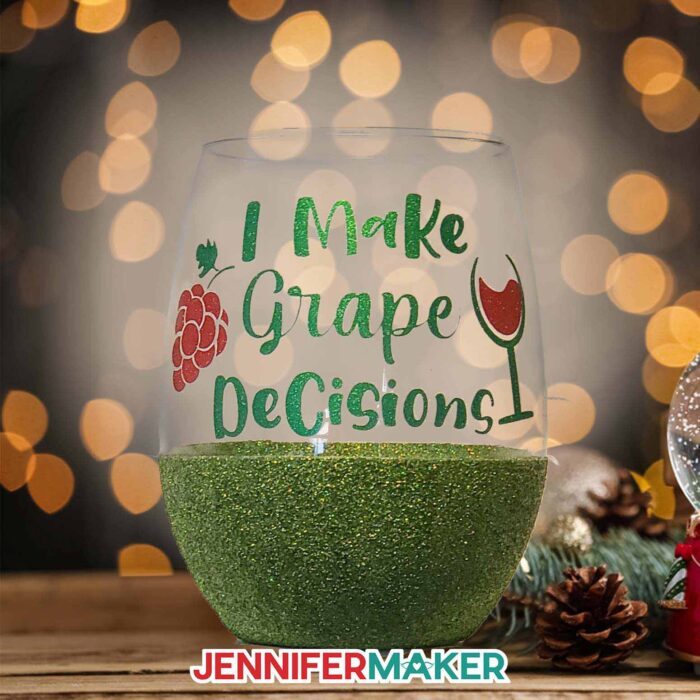 Stemless wine glass with green glitter bottom and a matching vinyl decal reading I make grape decisions with an image of grapes and a wine glass.