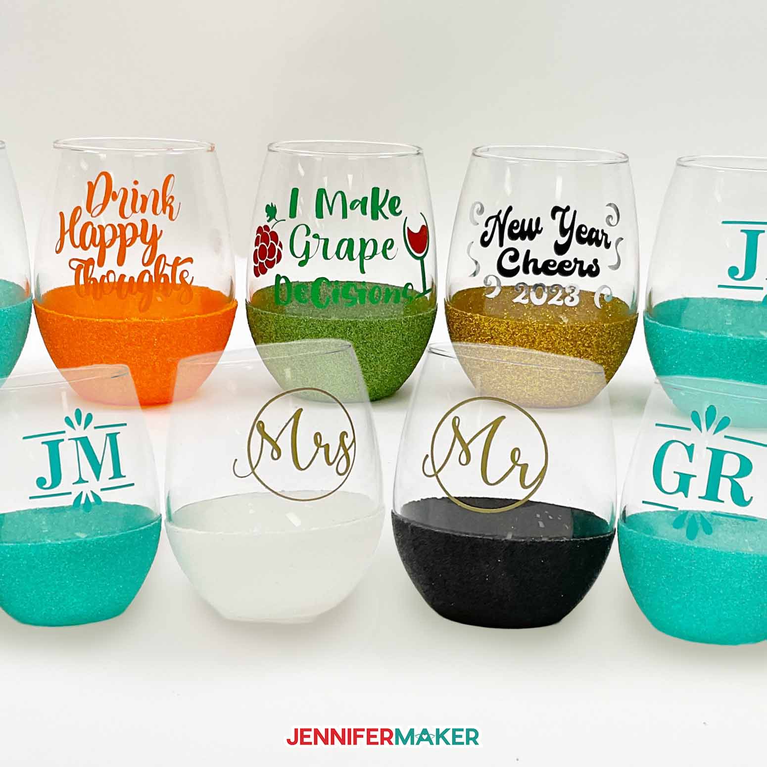 Several stemless glass wine glasses with glitter bottoms and vinyl decals from a tutorial on how to glitter wine glasses.