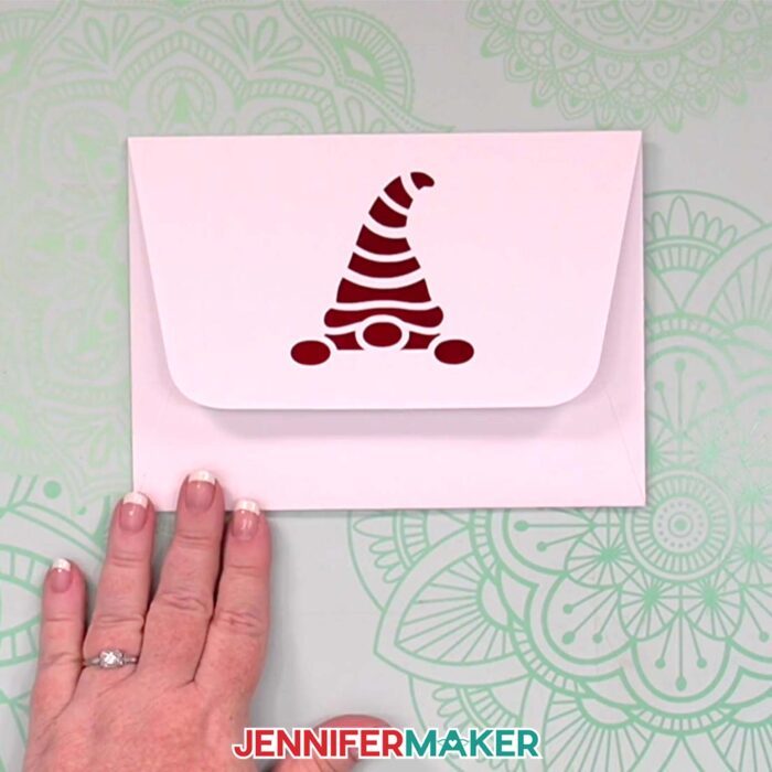 A white envelope with a metallic red cardstock backed cutout of a gnome head, from the Gnome Gift Set tutorial