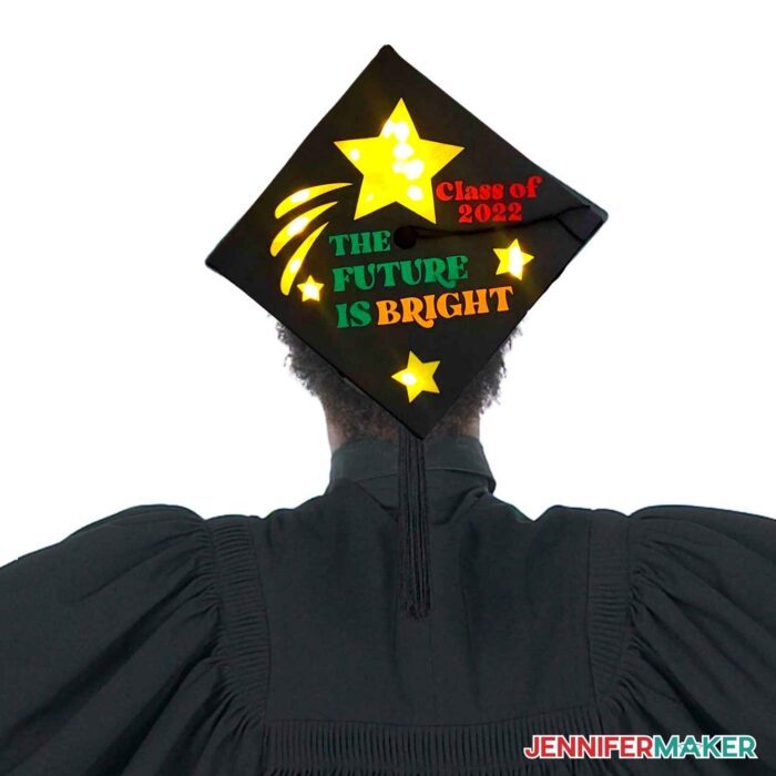 The back of a person wearing a decorated mortarboard and ceremony gown under the words Easy DIY Graduation Cap Ideas.