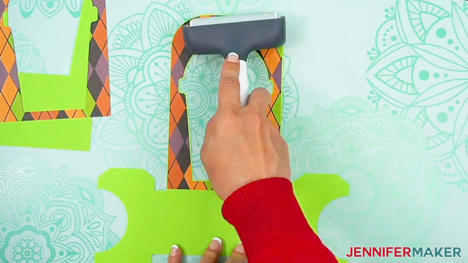 Use a brayer to make sure the glue is smoothed evenly between the layers of the Halloween treat cup holder base piece and decorative panel.