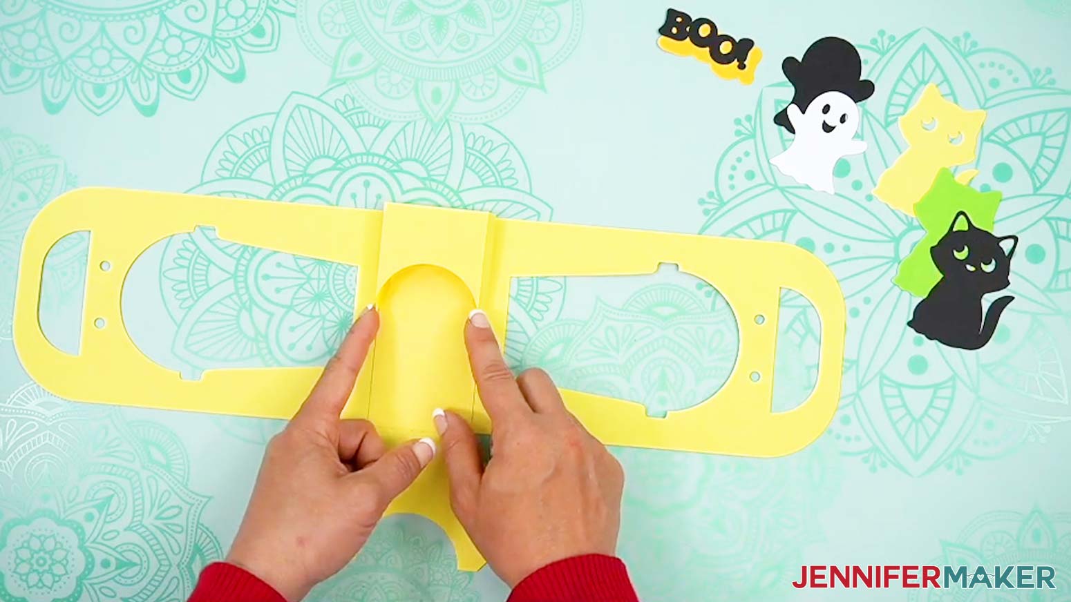 Hold the folded flap in place inside the Halloween treat cup holder to begin creating the cup pocket area.