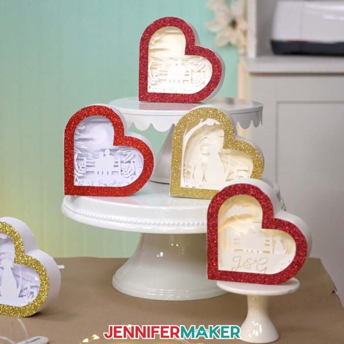 Make a Heart-Shaped Shadow Box with Jennifer Maker's tutorial! Four heart-shaped shadow boxes with red and gold glitter frames and different designs -- one customizable!