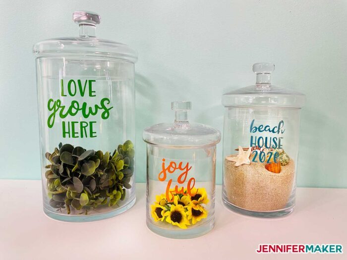 Glass apothecary jars with vinyl words and filled with faux plants, flowers, sand, and shells