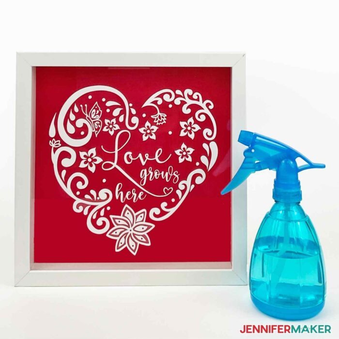 Spray bottle with water and a white vinyl shadowbox with a red background made with the wet vinyl transfer method