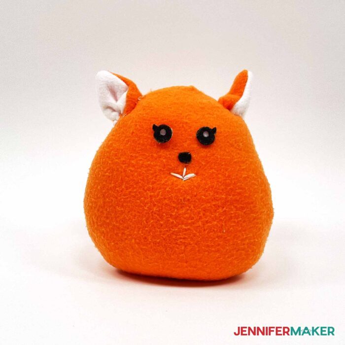 A stuffed cute plushie cat in orange fleece with sewn and felt details.
