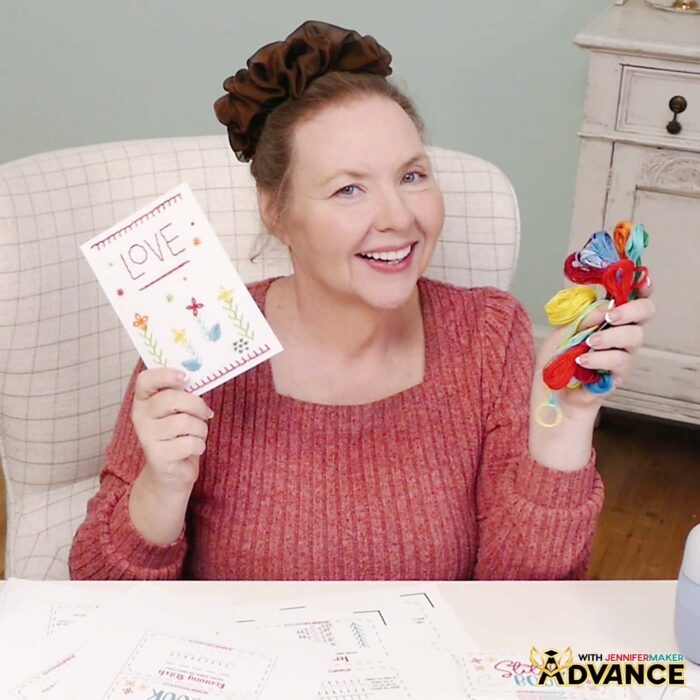 Jennifer holds up her custom design card in one hand, and a handful of colorful embroidery floss in the other.