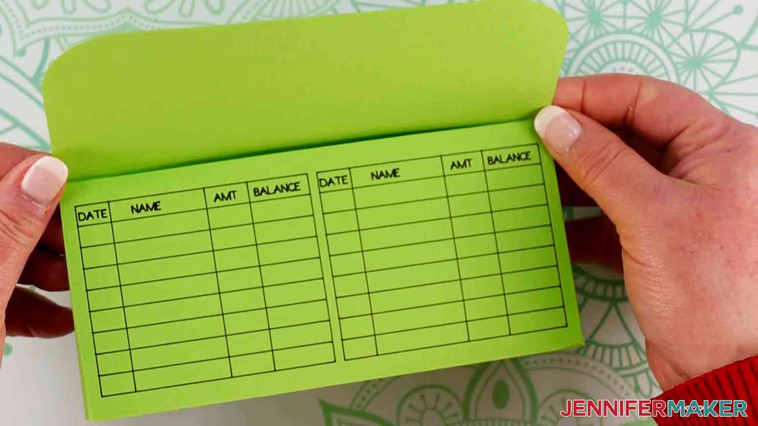 A woman's hands holding a rectangular green envelope with a grid for recording expenses on the exterior as part of the How to Make an Envelope tutorial