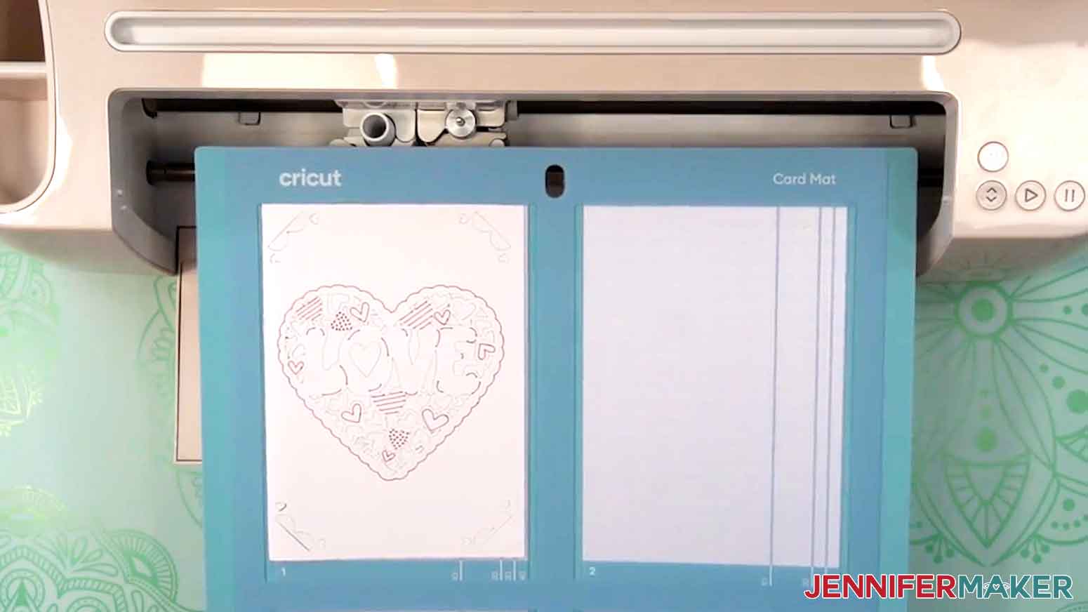 The card mat with the cut and drawn love design is removed from the Cricut.