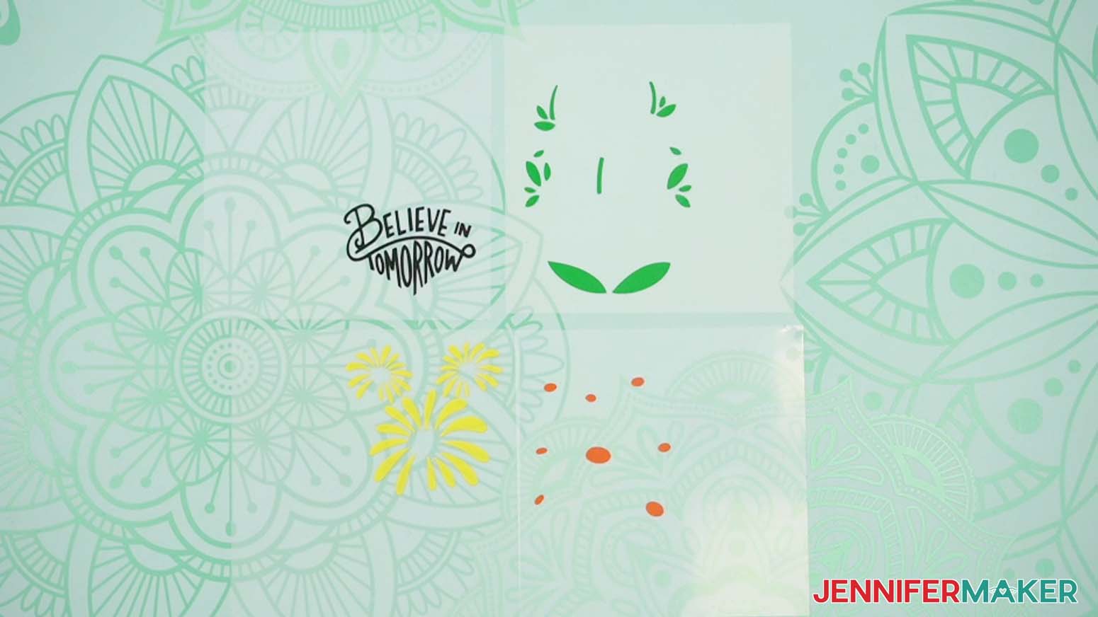 Weeded vinyl pieces - black text, green eaves, yellow flower petals, orange flower centers.