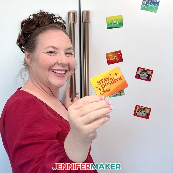 Jennifer stands in front of a fridge holding up a magnet that says "Stay positive."