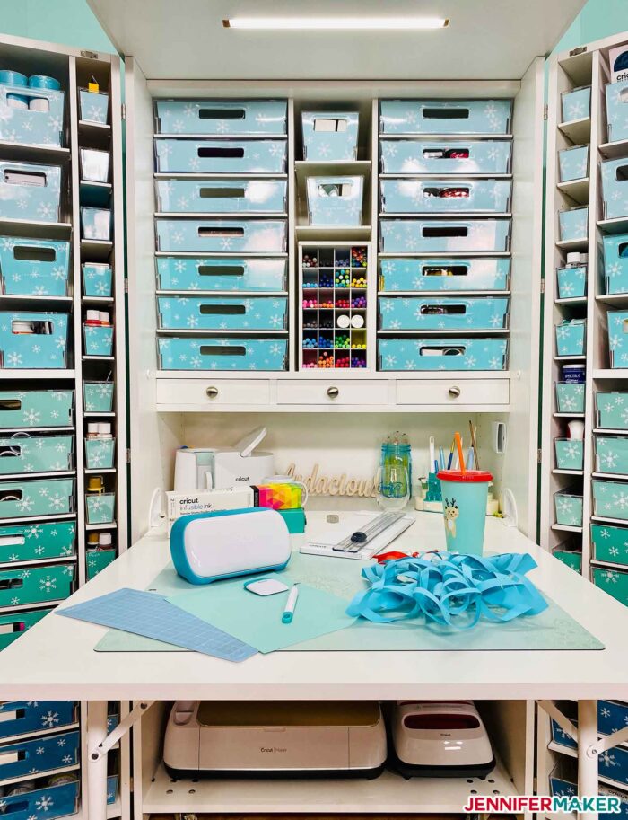 Dreambox table with Cricut Joy and a blue paper snowflake, plus craft supplies organized into totes