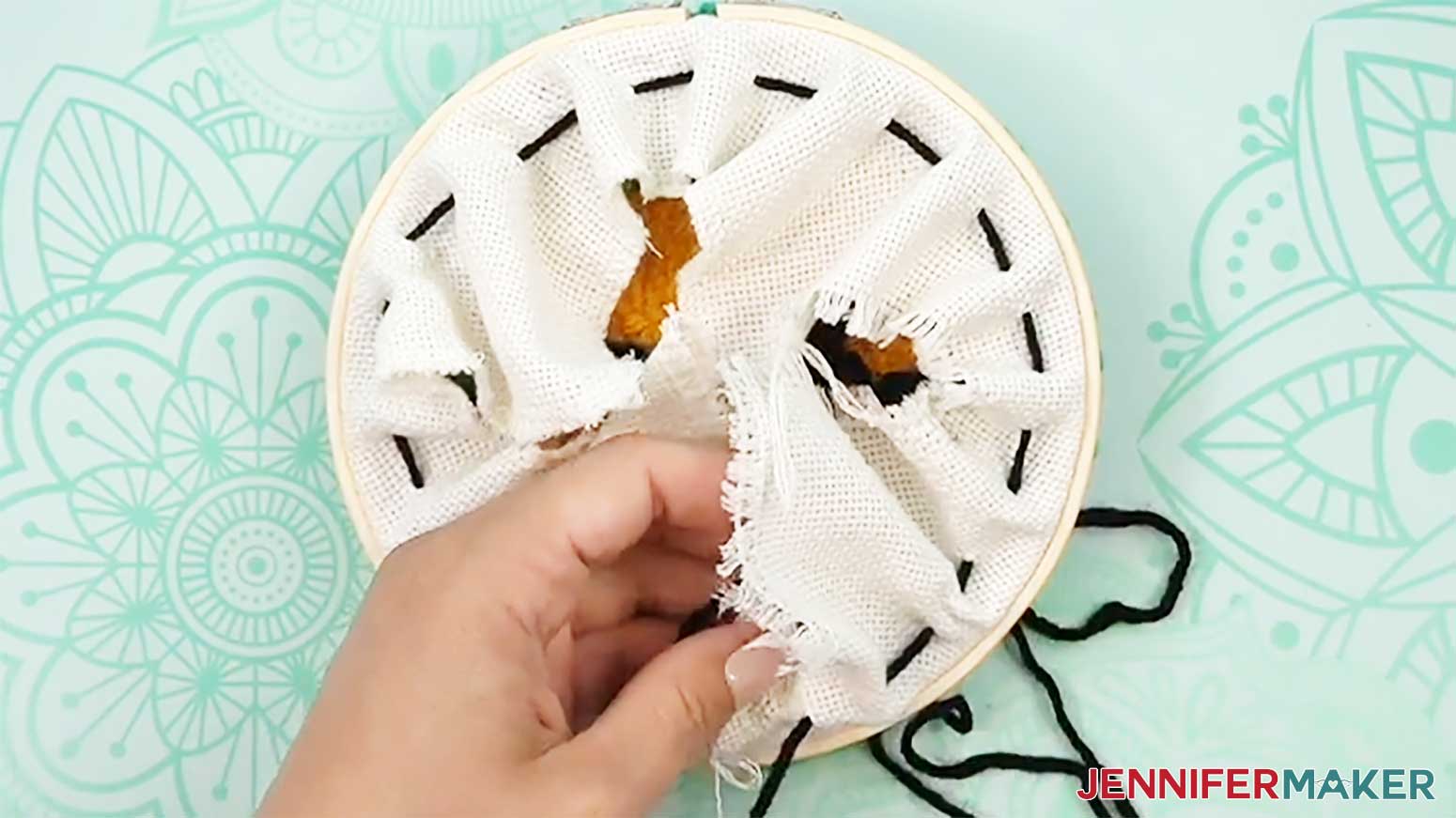 Weave the yarn around the entire piece of fabric to prepare to finish the back of the punch needle design.