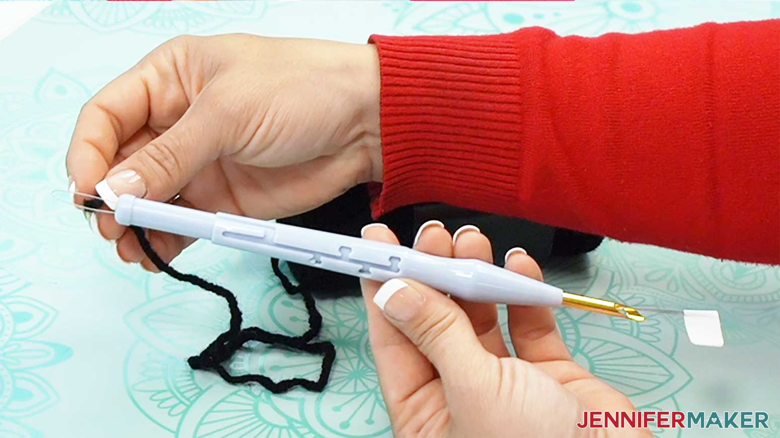 Push the yarn into the loop at the end of the needle threader to prepare to stitch the punch needle design.