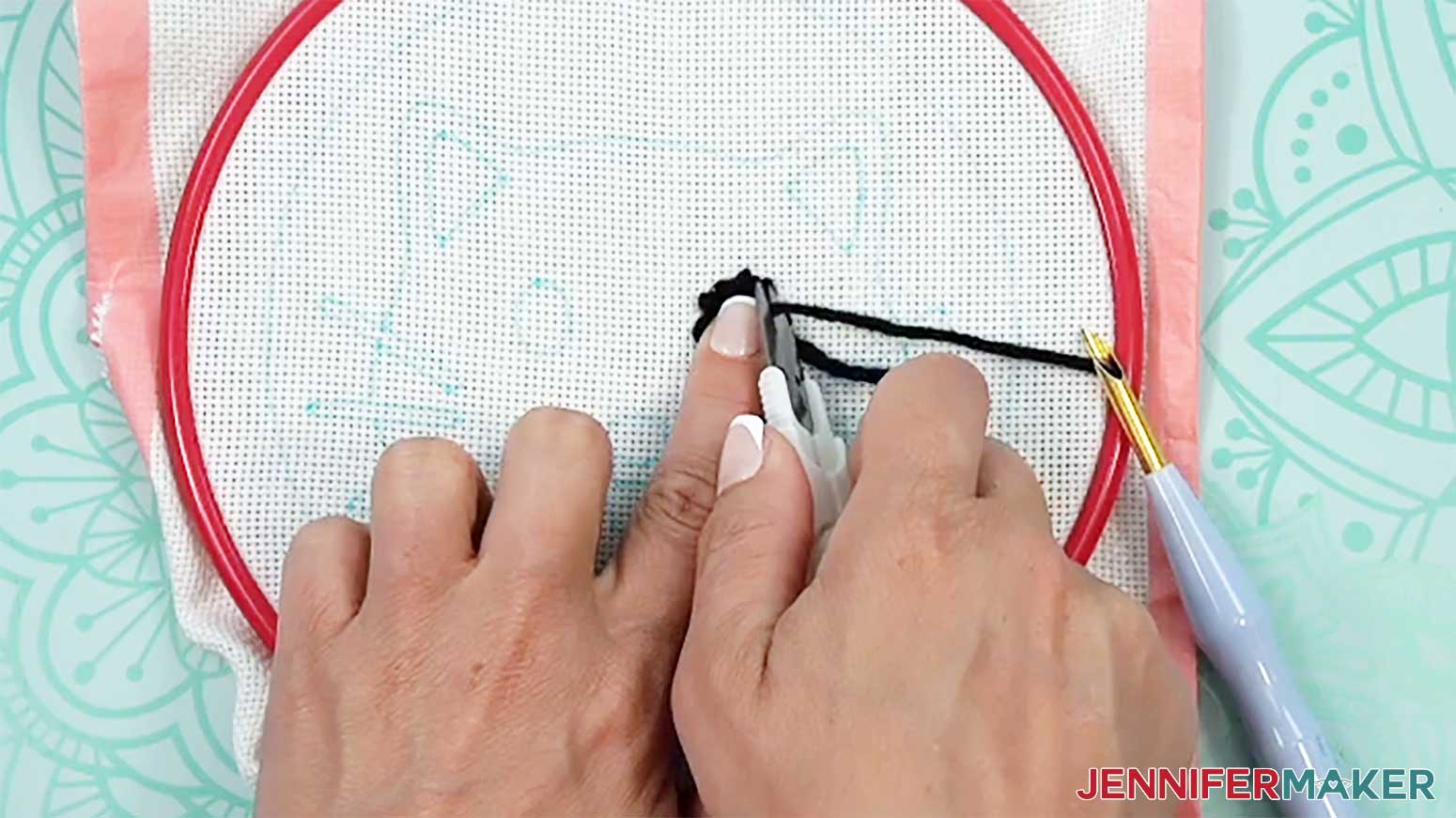 Hold the stitching in place while trimming the yarn close to the material of the punch needle design.
