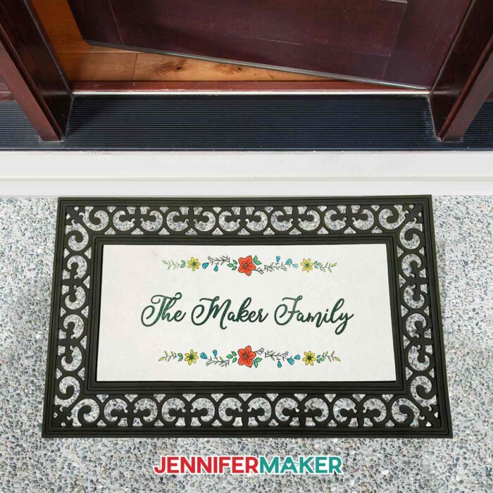 Sublimation doormat with The Maker Family and a floral border at a front door.