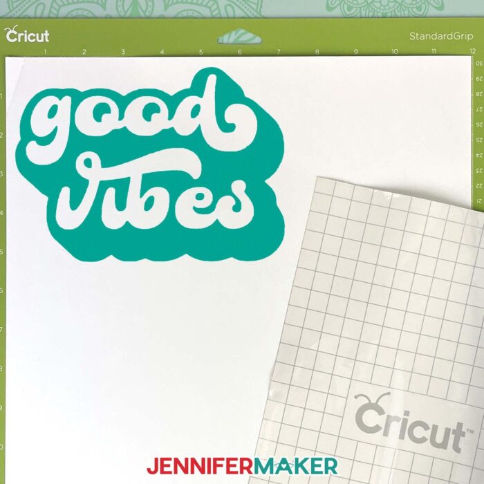 A green Cricut machine mat with a cut, weeded vinyl decal and transfer tape on its liner ready to transfer the design.