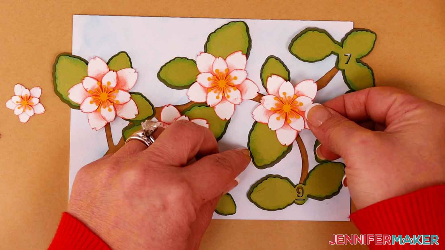 Apply craft glue to the back side of the cherry blossom flowers and attach them to the leaves.