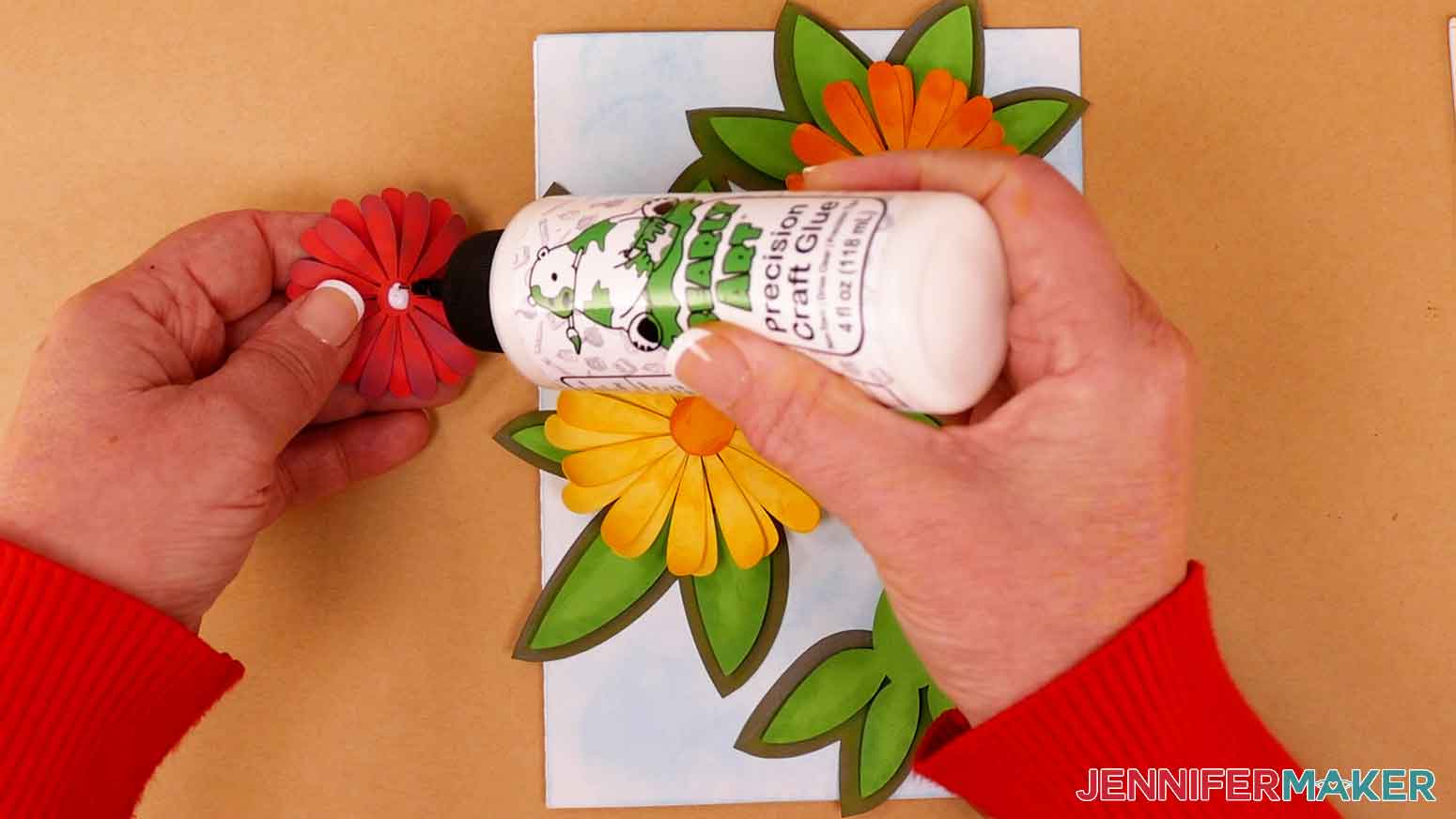 Apply craft glue to the back side of each daisy and attach them to the leaves on the card.