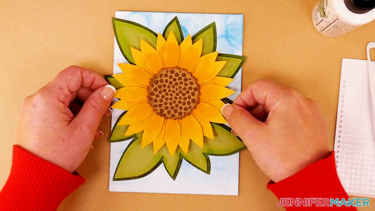 Apply craft glue to the back center of the sunflower and press the sunflower on to the leaf layers.