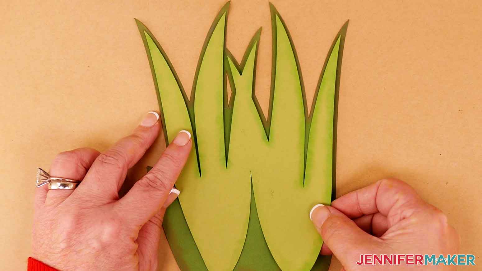 Align the light green leaf layer over the dark green leaf layer and press the green layers together.