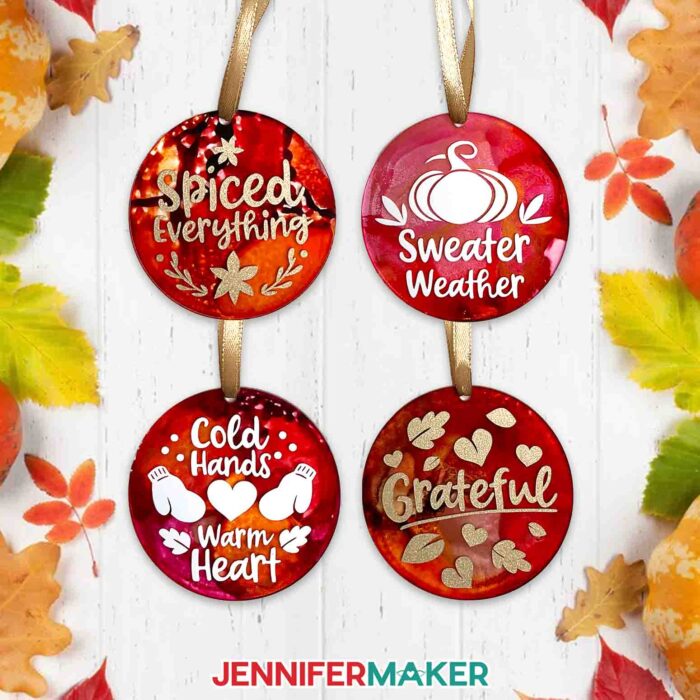 Four Alcohol Ink on Acrylic ornaments decorated in warm fall colors and cute seasonal quotes applied with cut vinyl
