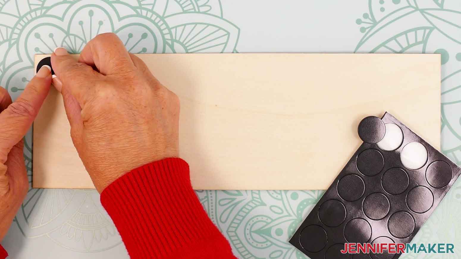 Place adhesive the first adhesive magnet to the upper left corner of the wood panel.