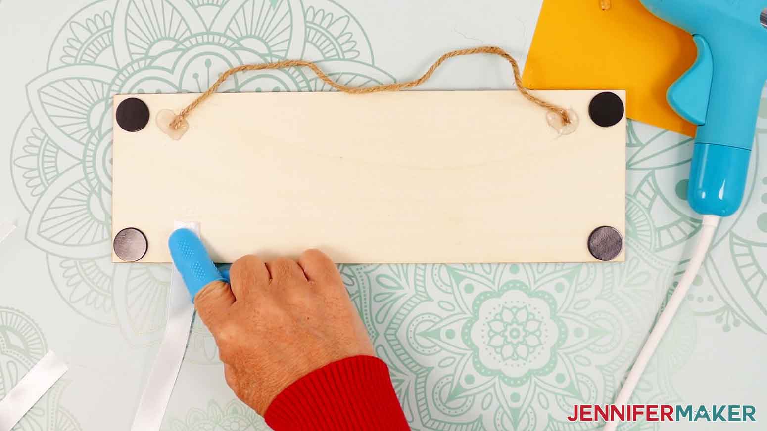 Place the first ribbon on the lower left of the panel and use hot glue to secure it to the wood.
