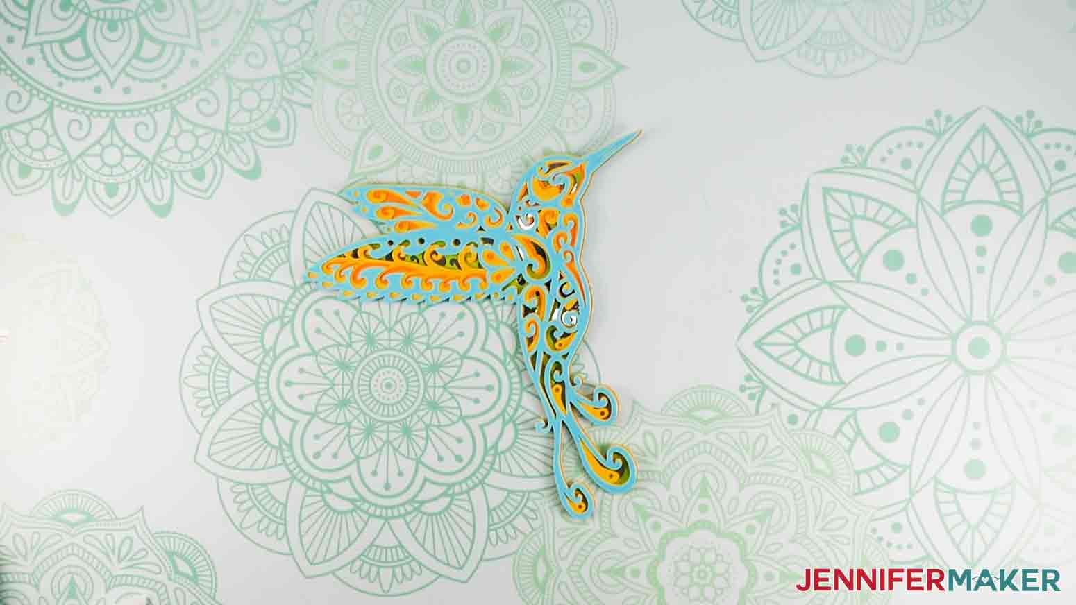 Completed layered humming bird project with intricate cuts on Cricut.