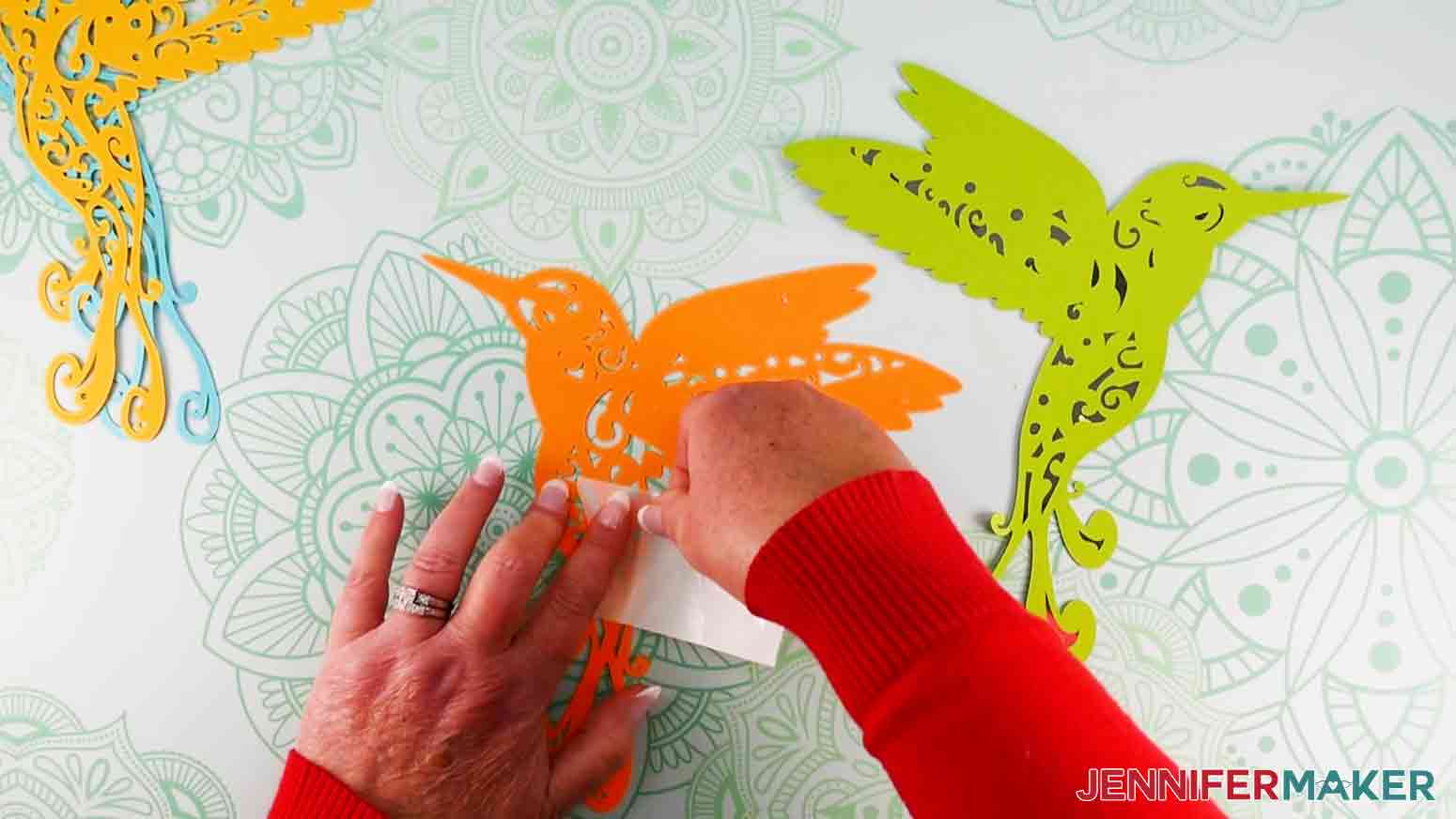 A crafter using the backing paper of a Zot adhesive to apply the glue to a cardstock.