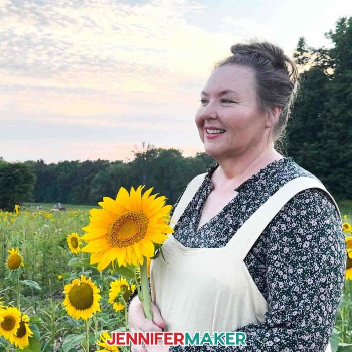 Jennifer Maker holding a sunflower in her garden.