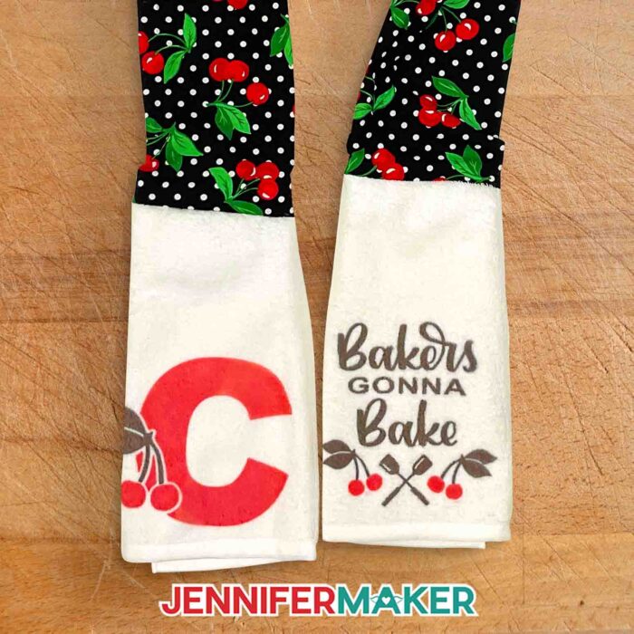 Kitchen boa scarf with black polka dot cherry fabric for the neck, Infusible Ink cherries and a capital C on one towel end, and a brush script "bakers gonna bake" on the other.