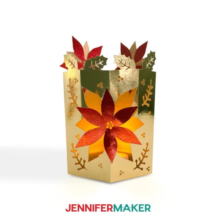 Make easy lantern pop-up cards with JenniferMaker's tutorial! A beautiful pop-up lantern cards with poinsettias and berries cut out, made from metallic gold and red cardstock, stands up, lit from the inside by a battery-operated tealight candle.