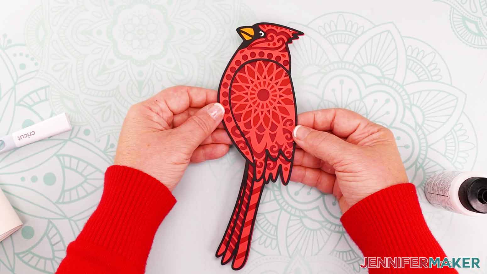 Two hands holding the finished cardinal for the cardinal svg project