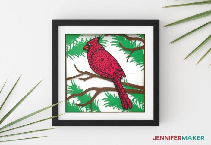 Cardstock layered cardinal SVG project in a black shadow box frame.