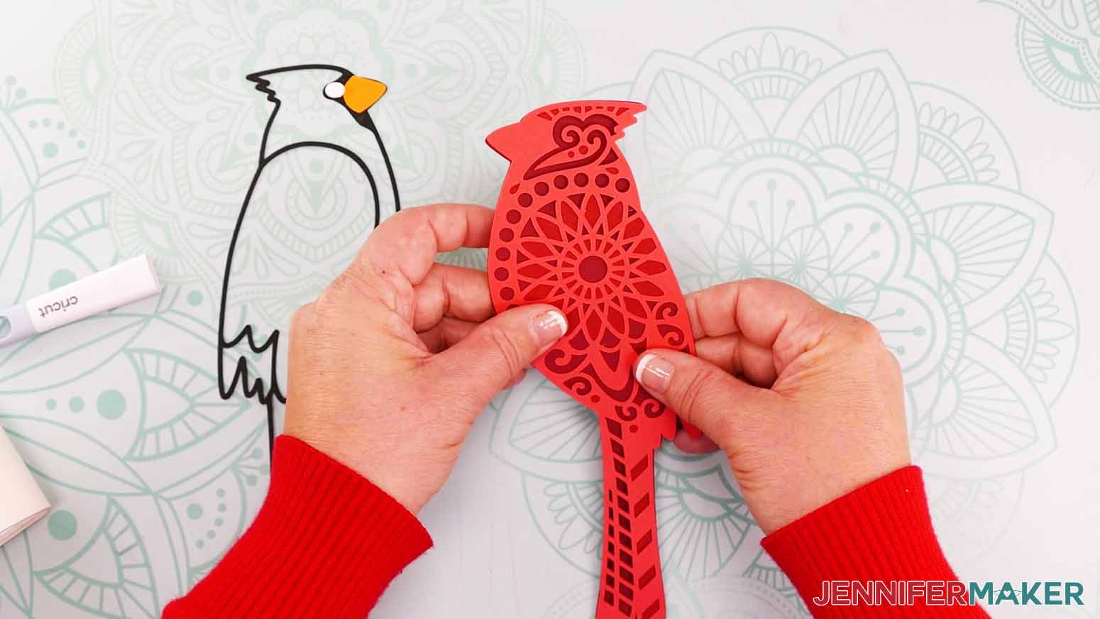 Two hands holding the three attached red cardinal pieces for the cardinal svg project