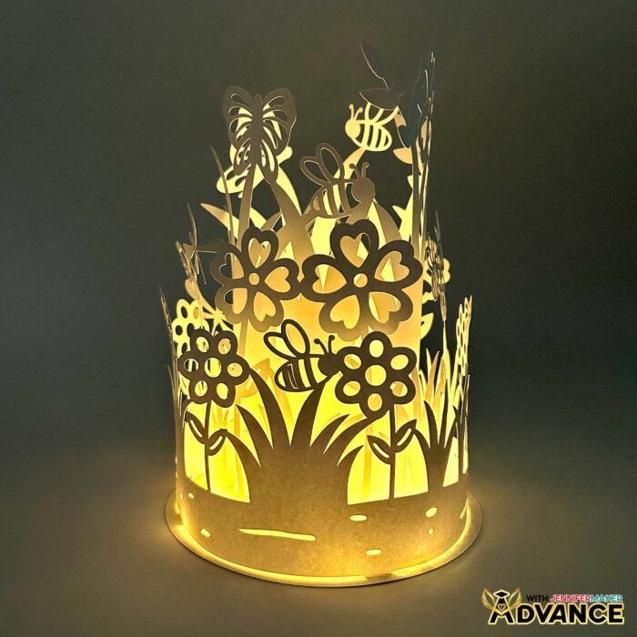 Customized Layered Garden Lantern with cylindrical tiers of white paper and intricate cutouts of leaves, roses, bees, and butterflies, glowing in a dark space
