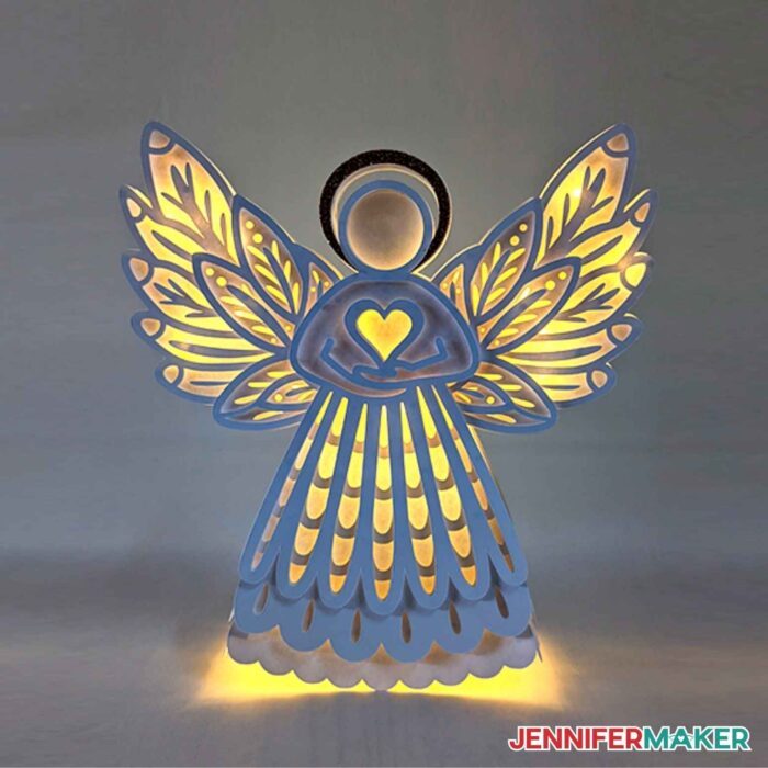 White paper angel with lights illuminating in the background