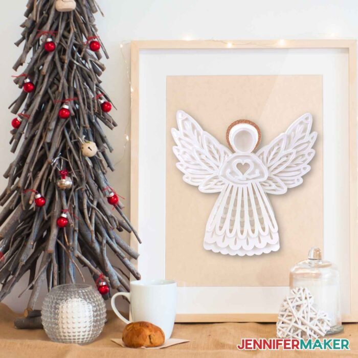 White paper angel inside frame next to a mini Christmas tree