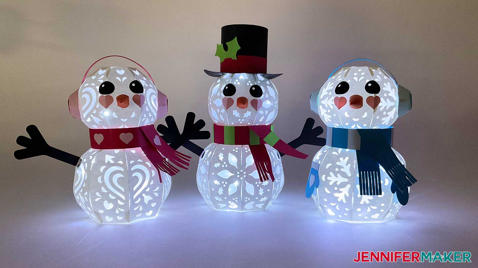 Assembled Valentine's Day, Christmas, and Winter light up paper snowmen placed side by side with lights illuminating them from the inside